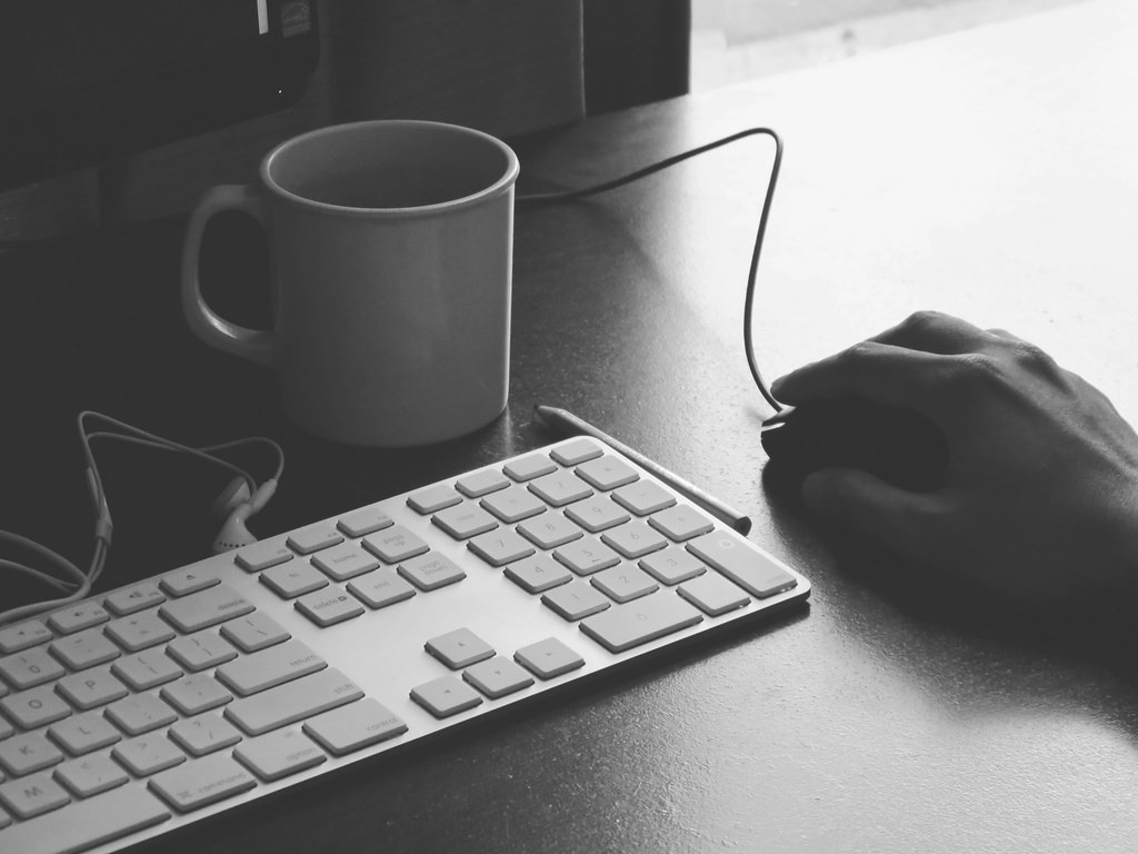 Taza de café junto a un teclado mientras se redacta un correo