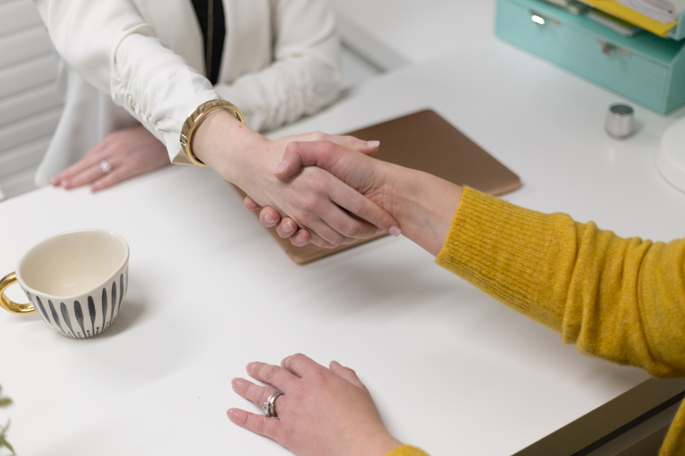 Dos personas dándose la mano sobre una mesa