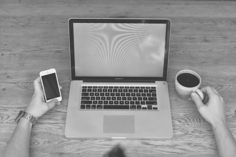 Escritorio en blanco y negro con portátil, móvil y café