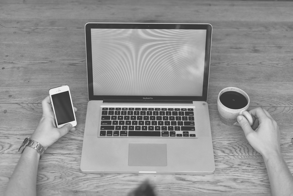 Escritorio en blanco y negro con portátil, móvil y café